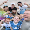 A group in matching blue soccer jerseys posing for a selfie