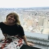 Someone sitting by a window high above a city skyline