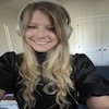 A person wearing a black top and headphones, smiling