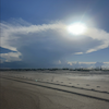 The sun shining through clouds over a flat landscape